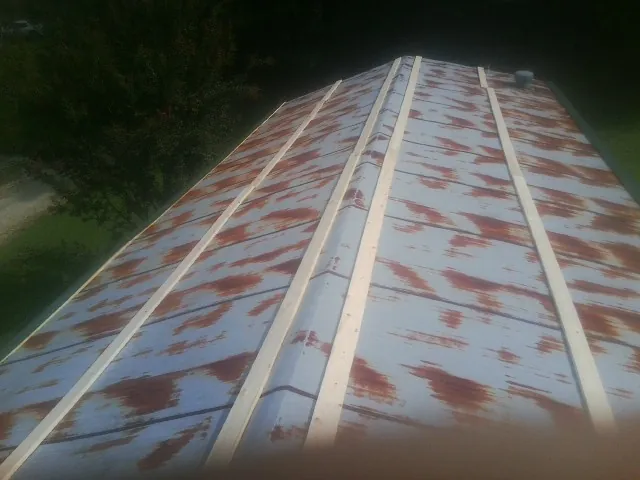 Rusted metal roof panels with new wood purlins before replacement — Storm Damage Roof Repair in Amery by Roofing Brothers