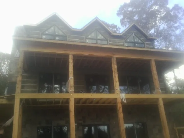 Dormers and porch framing on a large log home under construction — Roof Coating work by our crew in Amery