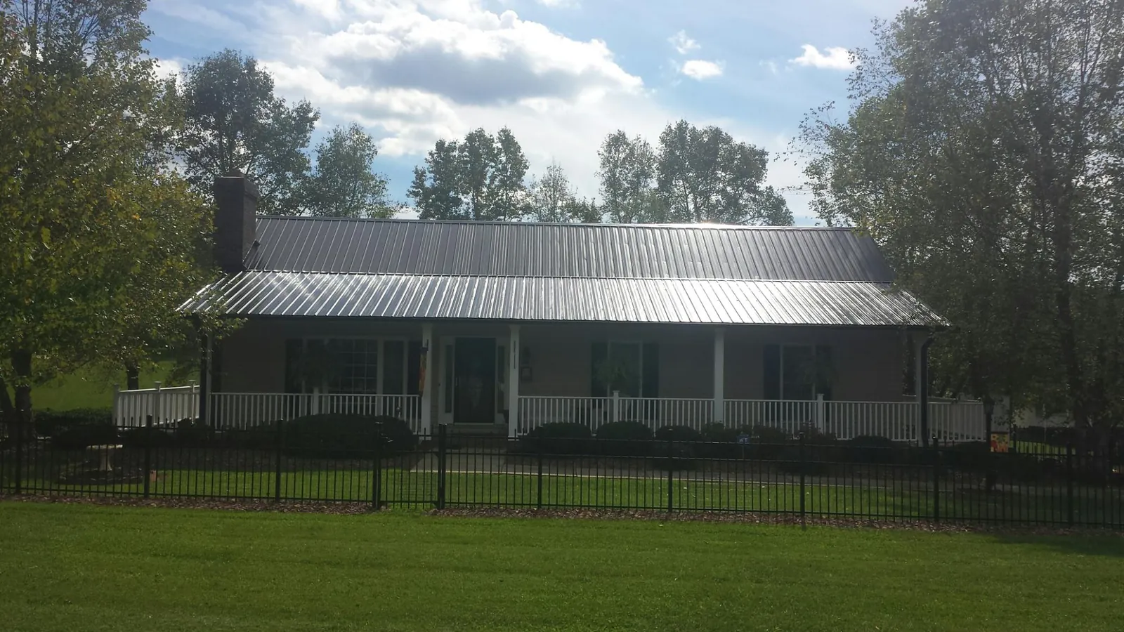 Gray metal roof on a brick ranch with a full width front porch — Gutter Guard Installation work by our crew in Amery