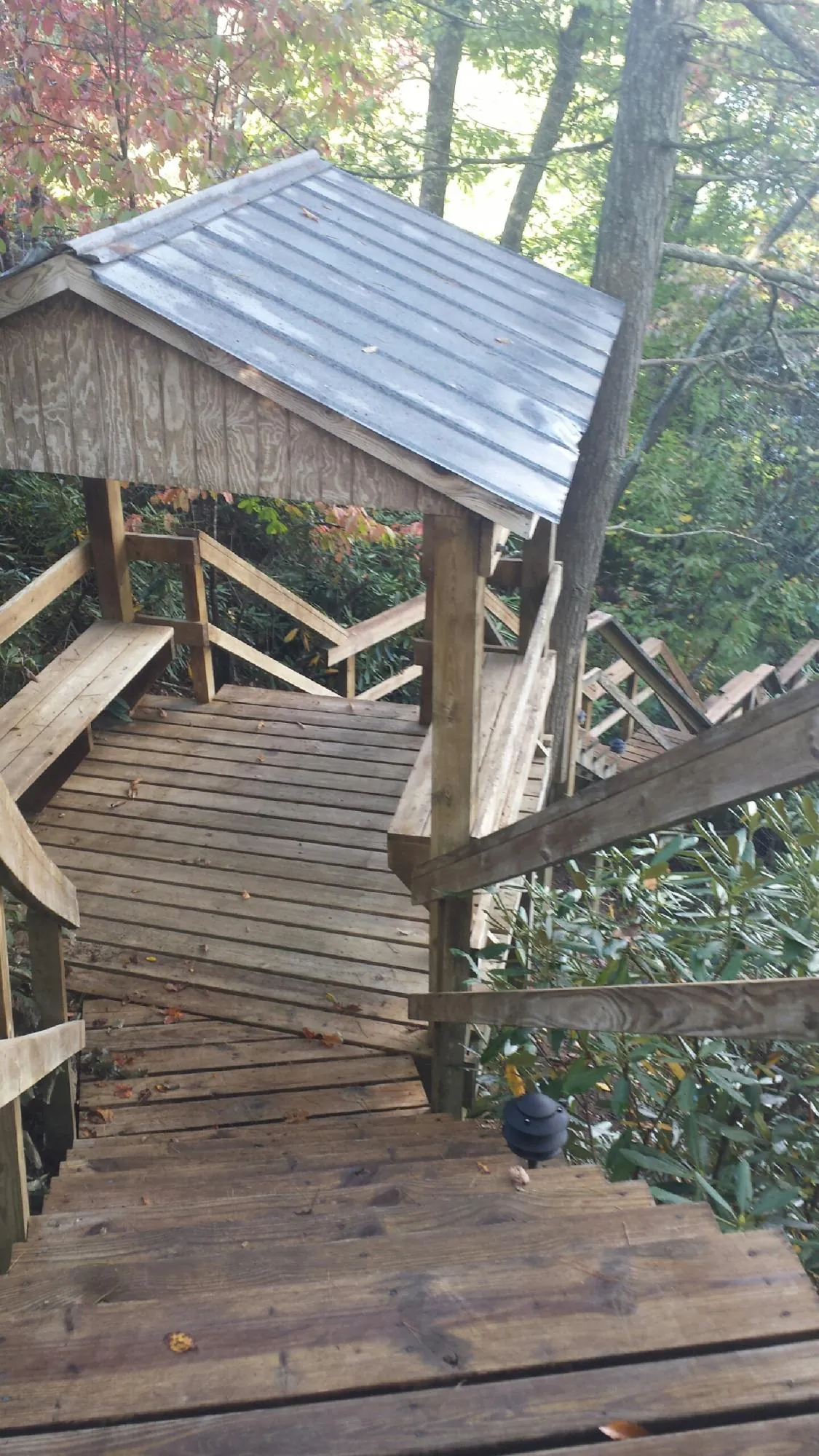 Metal roofed shelter over wooden steps on a wooded walkway — Skylight Repair & Installation work by our crew in Amery