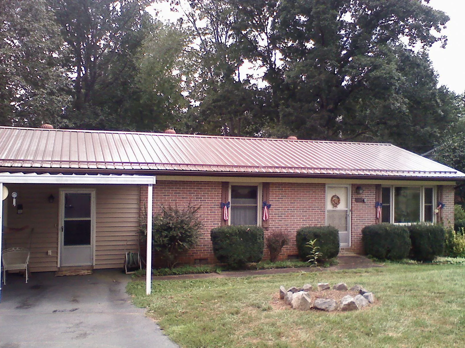 Bronze metal roof and carport on a brick ranch home — Roof Repair work by our crew in Amery