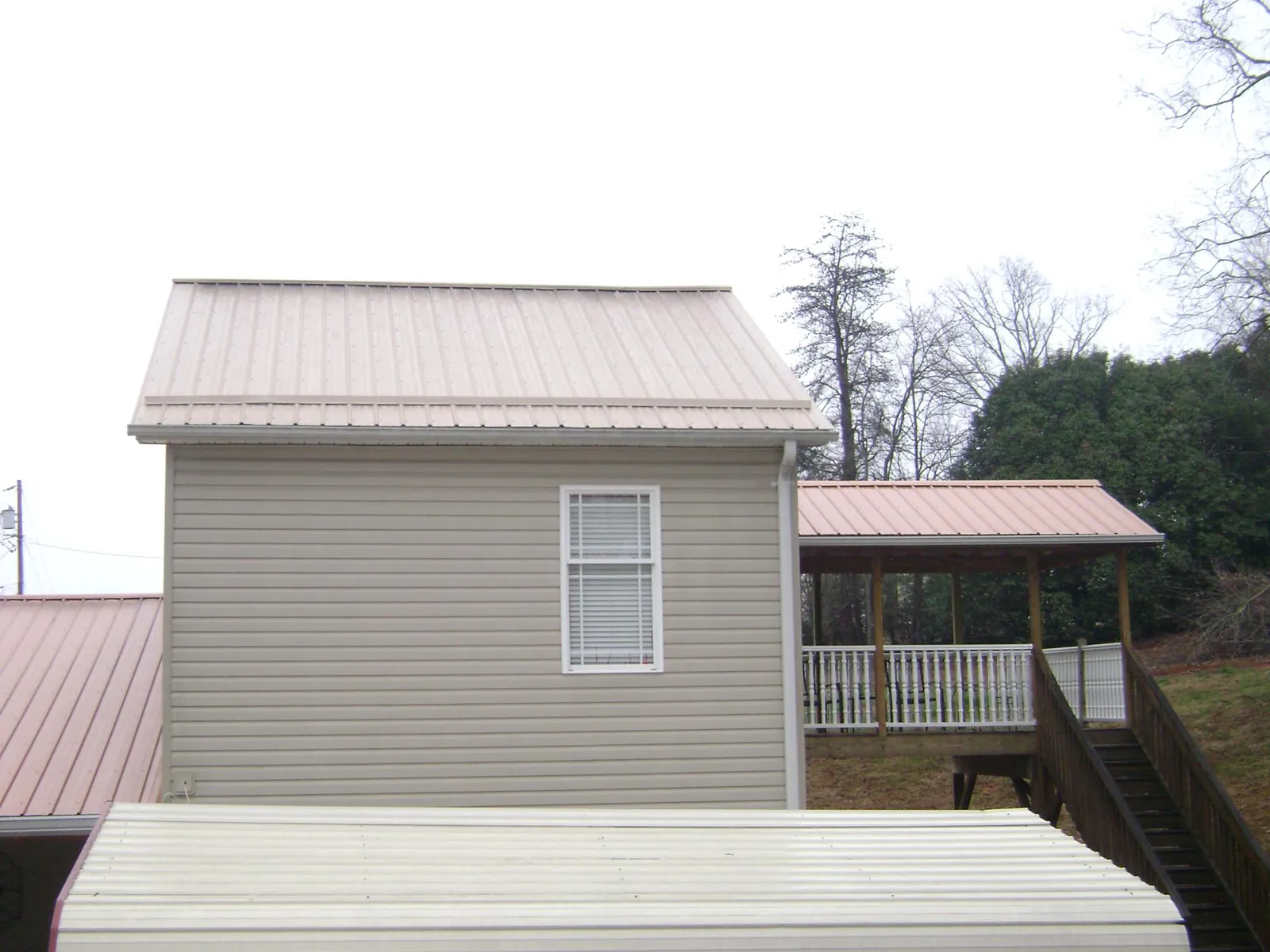 Tan metal roofs on a two story addition and attached porch, from a Roof Replacement job in Amery