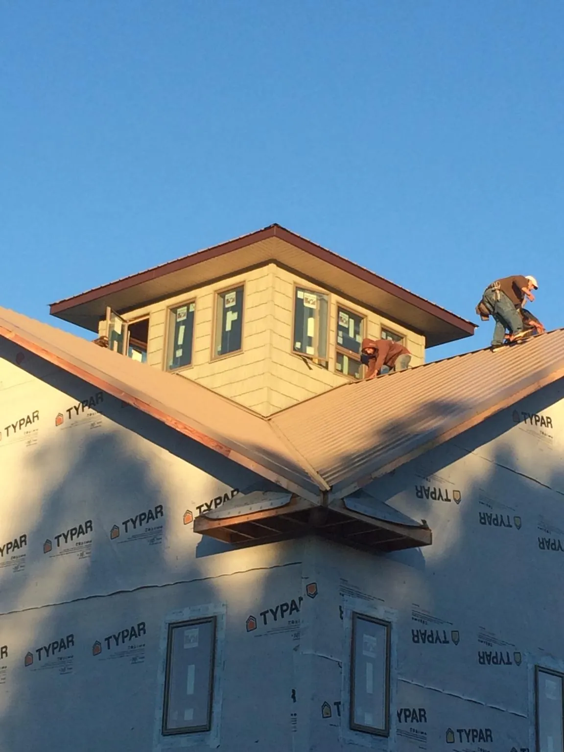 Roofers working around a rooftop cupola on a new metal roof at sunset — Roof Waterproofing in Amery by Roofing Brothers